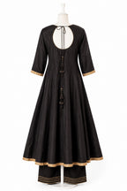 Black dress with gold trim on a white mannequin against a white background