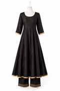 Black dress with gold trim on a mannequin against a white background
