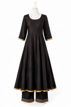 Black dress with gold trim on a mannequin against a white background