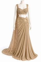 A beige and gold traditional Indian gown displayed on a white mannequin against a white background. The dress features a heavily embellished gold beaded crop top, a draped beige skirt with a circular waist detail, and a matching sheer embroidered dupatta.