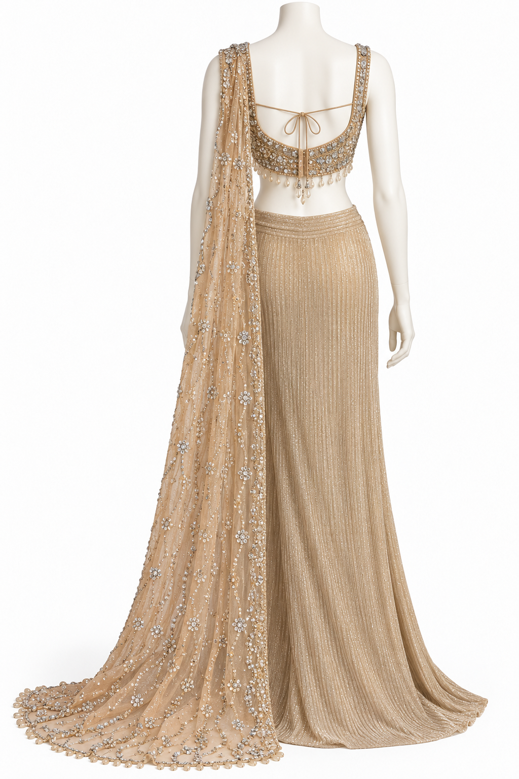 A beige and gold embellished traditional Indian gown displayed on a white mannequin. The dress features a pleated skirt, a matching sleeveless blouse with intricate gold embroidery and beadwork, and a sheer dupatta draped over one shoulder.