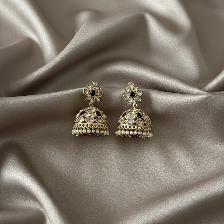 Pair of gold and black earrings on a satin surface