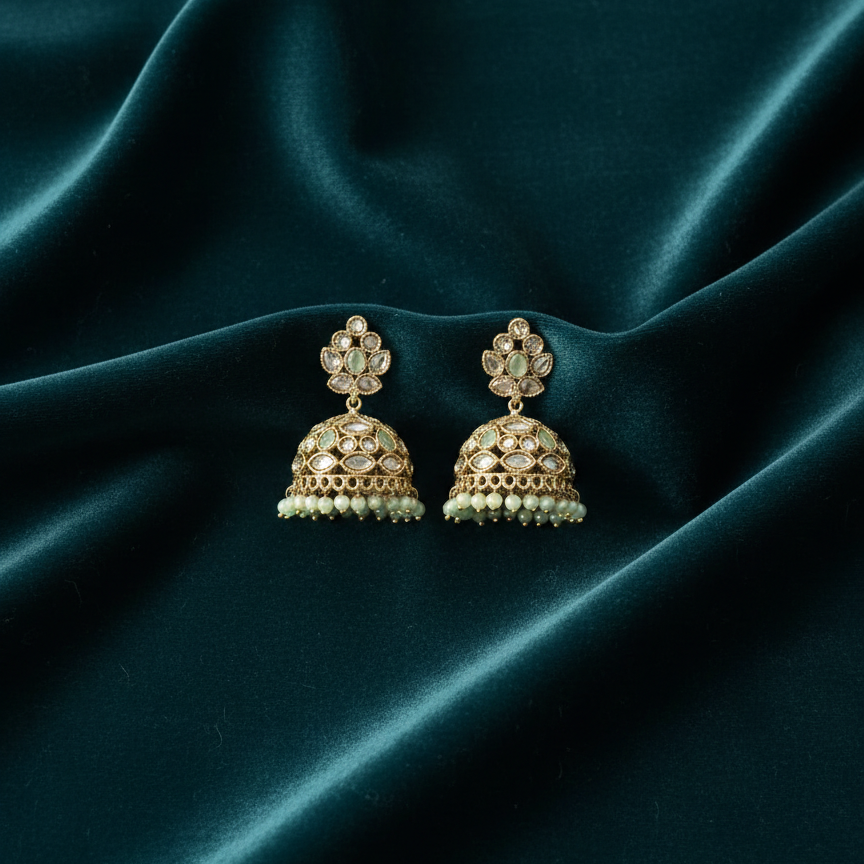 Gold and pearl earrings on a dark teal fabric background