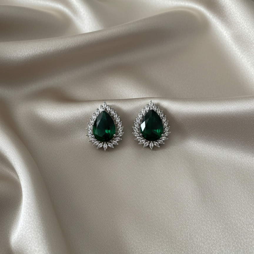 Pair of green gemstone earrings on a satin surface