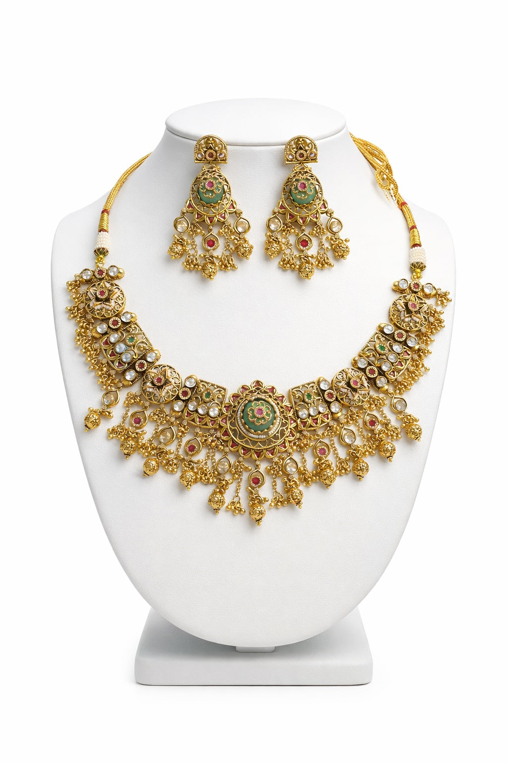 Gold necklace and earrings set on a white stand