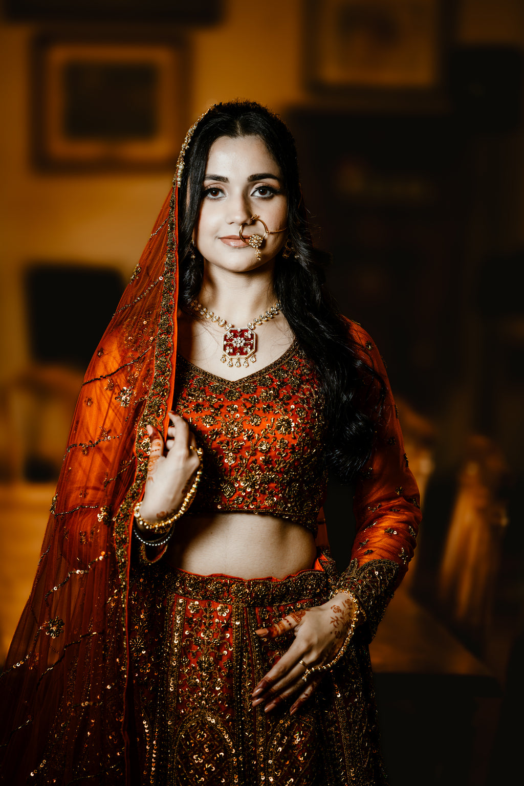 Woman in traditional red and gold outfit with jewelry against a blurred background