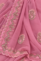 Pink georgette saree fabric with detailed gold and silver embroidery, featuring paisley motifs and scalloped borders.