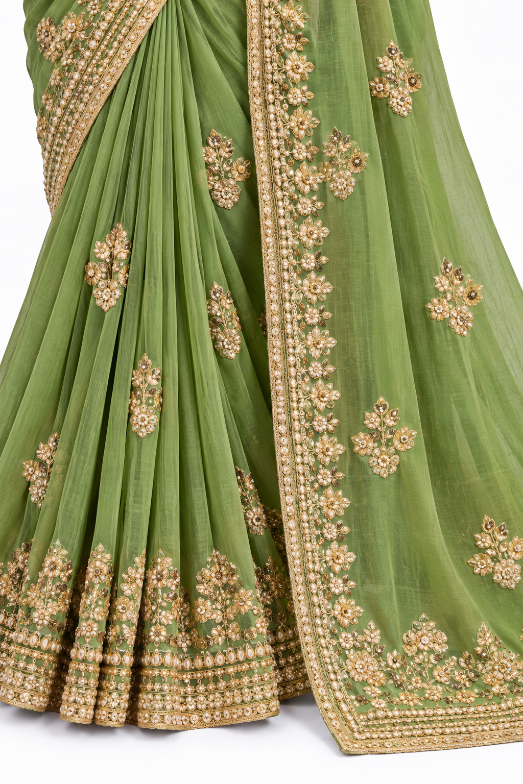 A close-up of a sage green georgette saree with intricate gold and silver floral embroidery along the border and scattered motifs on the body.