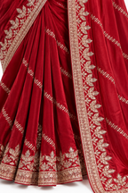 A close-up of a deep red silk saree with intricate gold zari embroidery, showing the pleated body and the border design.