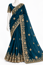 A dark teal blue saree with intricate gold floral embroidery, displayed on a white mannequin against a plain white background.