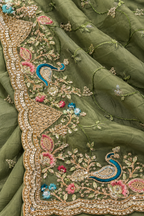 An olive green embroidered fabric, likely a dupatta or scarf, featuring detailed gold zari embroidery, sequins, and colorful floral and peacock motifs.