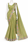 A light olive green saree with a matching sleeveless blouse, displayed on a white mannequin. The saree features a shimmering metallic texture, a multicolor floral patterned border, and a matching embroidered border on the pallu.