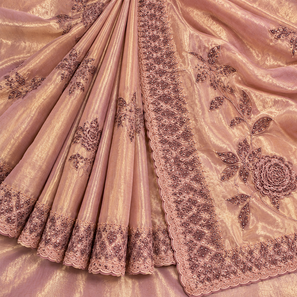 A close-up of a draped pink fabric with metallic sheen, featuring dark floral embroidery and scalloped lace borders.