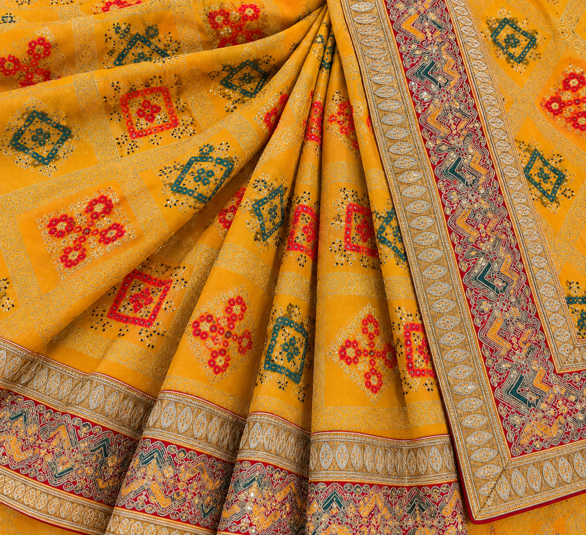 A close-up of a draped yellow fabric, likely a sari, featuring intricate woven geometric and floral motifs in red, teal, and gold, with detailed borders.