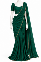 A dark green georgette saree with gold foil dot embellishments and a gold border, displayed on a white mannequin with a matching green short-sleeve blouse.