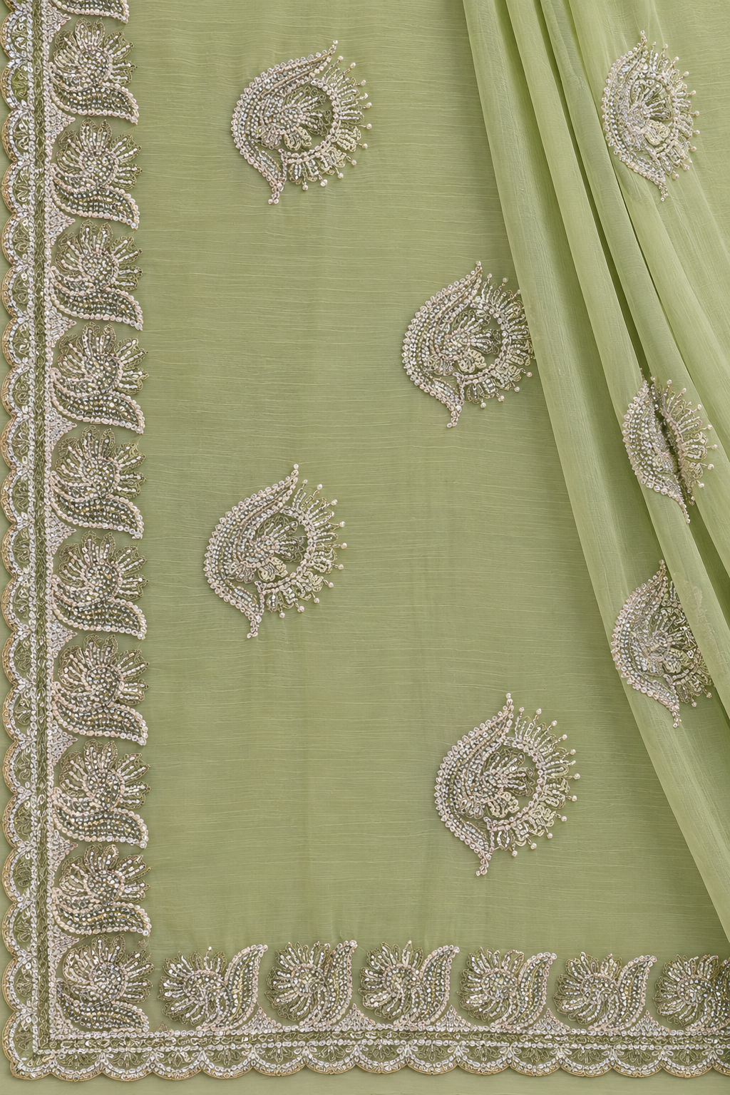 A sage green organza saree or fabric panel with intricate silver and white embroidery, featuring a decorative border and matching embroidered motifs.