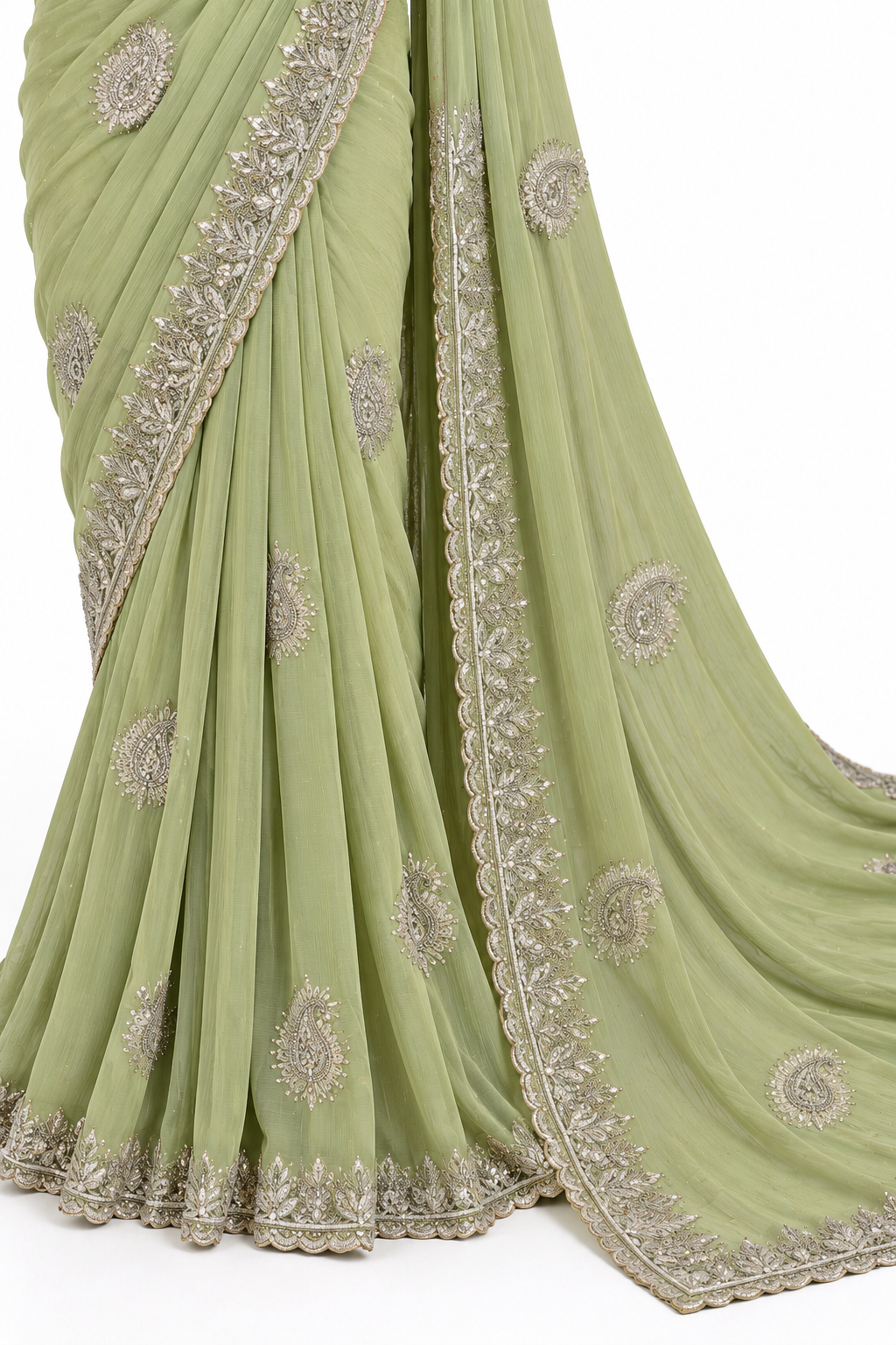 A sage green georgette saree with intricate silver and gold embroidery, shown draped elegantly against a plain white background.
