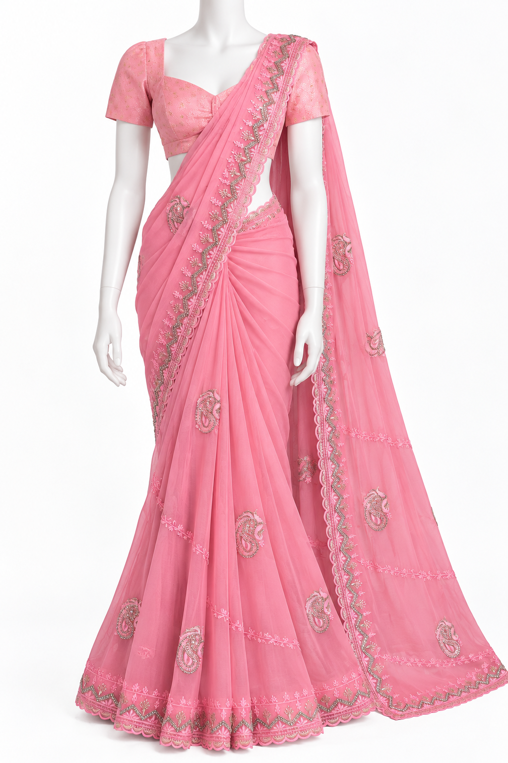 A pink georgette saree with a matching short-sleeve blouse, displayed on a white mannequin. The saree features silver and gold embroidery along the border and scattered motifs on the fabric.