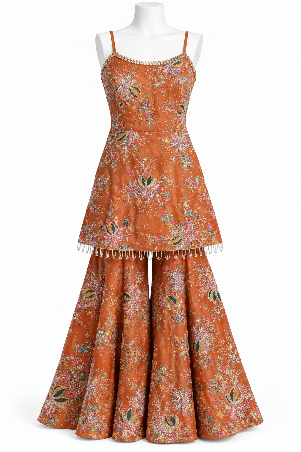 An orange two-piece salwar suit set with a floral print, displayed on a white mannequin against a white background. The set includes a sleeveless top with thin straps and a matching flared bottom.