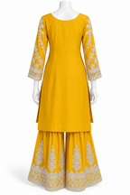 A yellow three-piece traditional outfit displayed on a white mannequin, featuring a straight kurta with white floral embroidery on the sleeves and hem, matching flared sharara pants, and coordinating belt.