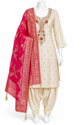 A traditional Indian salwar kameez suit displayed on a white mannequin. The outfit features a cream-colored kurta with gold embroidery and red floral accents, paired with cream-colored patola pants and a bright pink dupatta with intricate gold zari patterns.