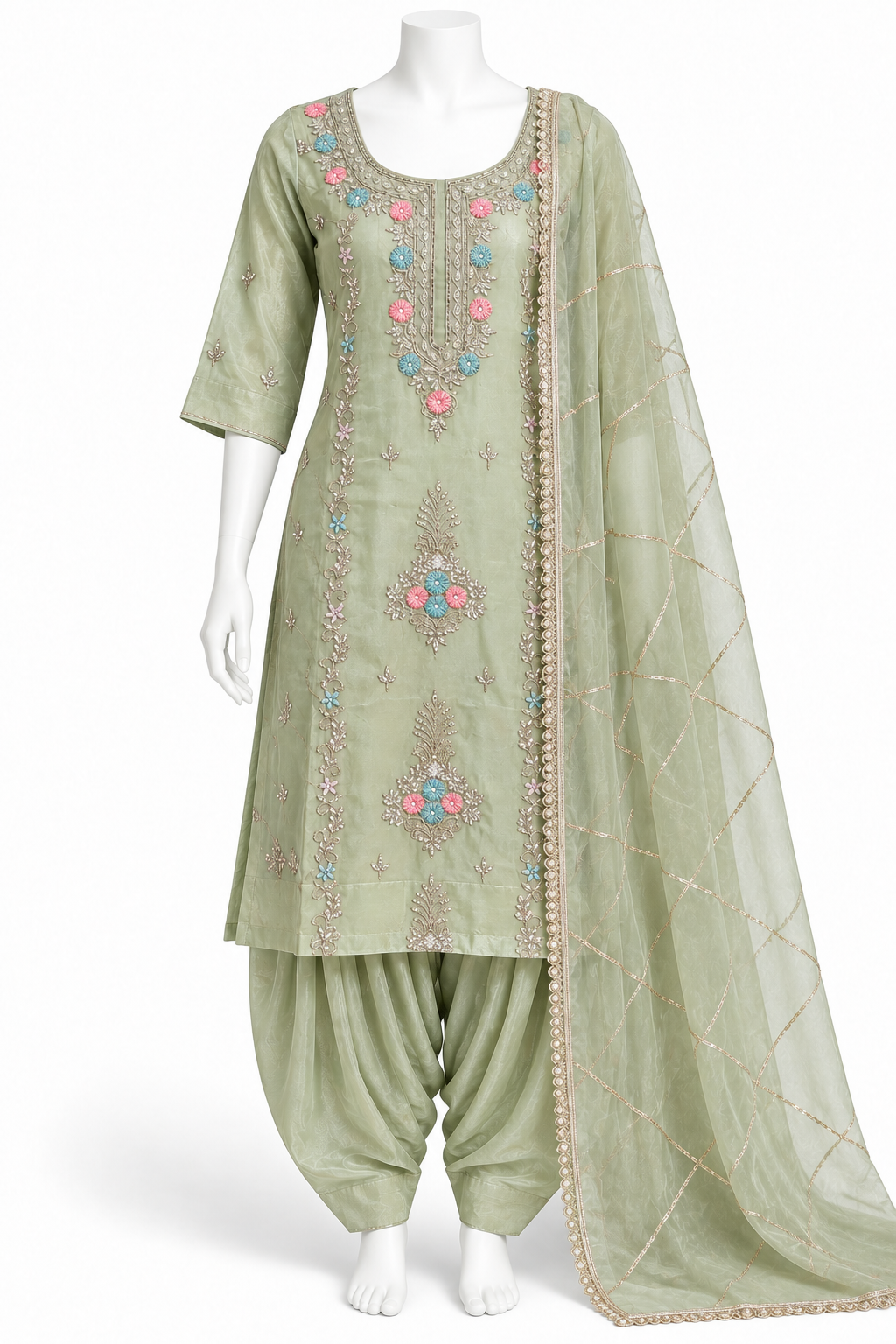 A sage green Indian ethnic suit set displayed on a white mannequin, featuring a kurta with colorful floral embroidery, matching pants, and a sheer dupatta.