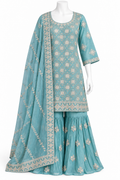 A three-piece traditional outfit displayed on a white mannequin, featuring a turquoise blue kurta and flared sharara pants with beige floral embroidery, accompanied by a matching sheer dupatta.