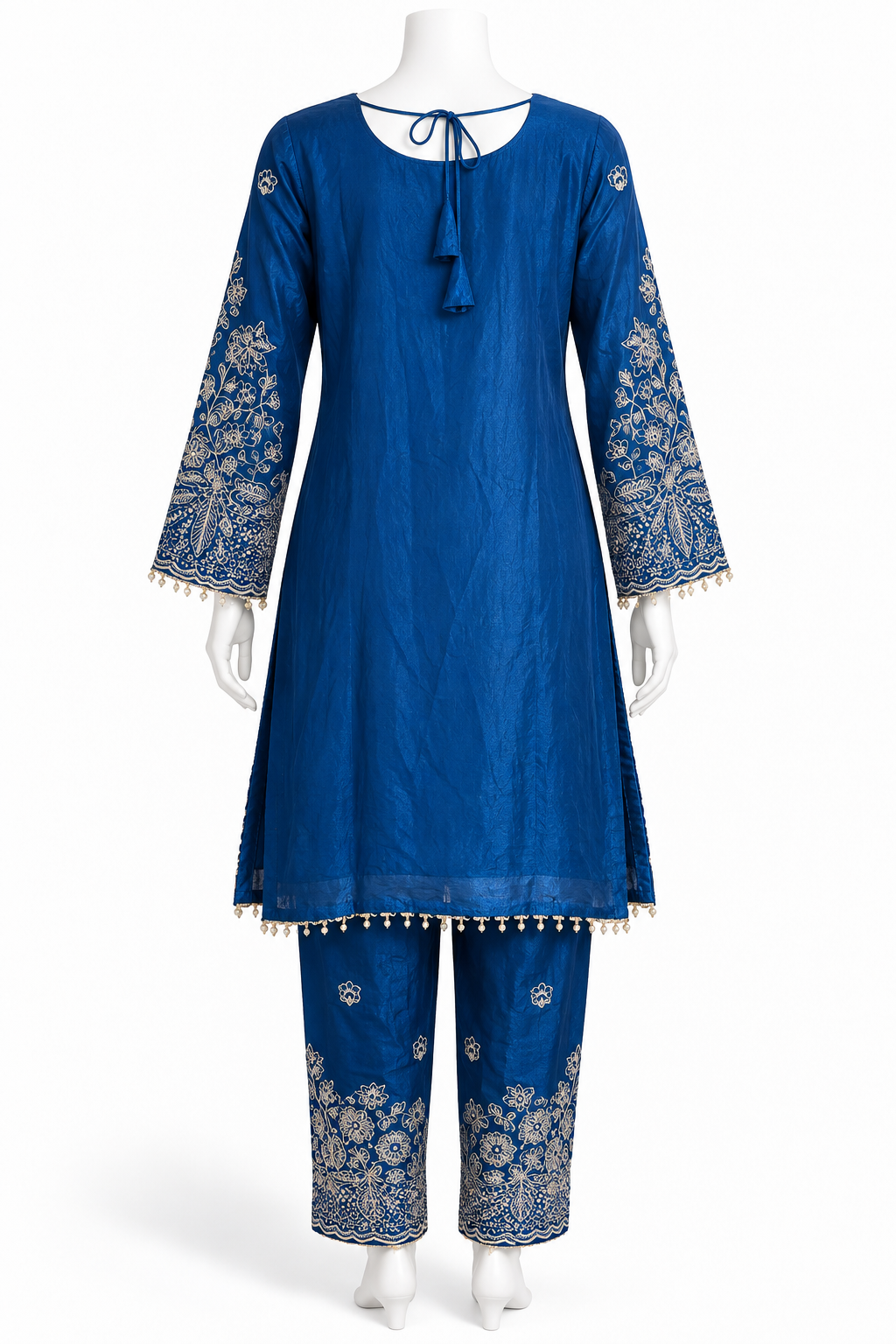 A royal blue kurta and pant set displayed on a white mannequin. The kurta features long sleeves with intricate gold floral embroidery and tassel trim, a drawstring neckline, and a matching tassel hem.