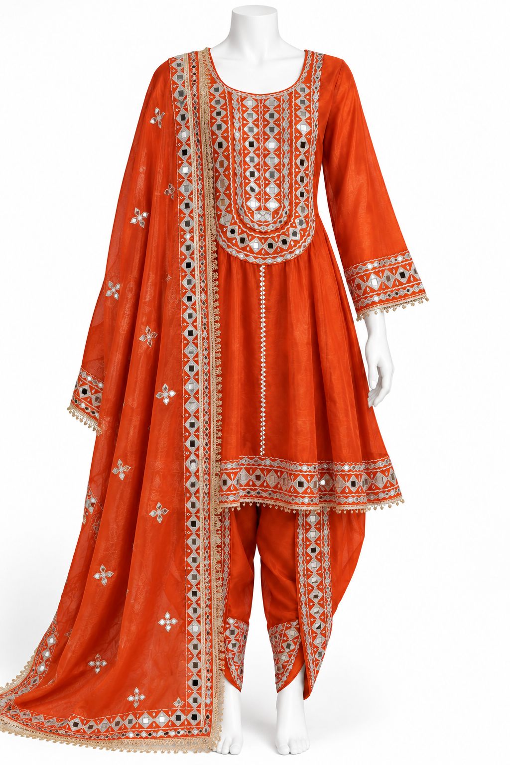 An orange traditional Indian salwar kameez suit set with intricate silver, white, and black embroidery, displayed on a white mannequin against a white background.