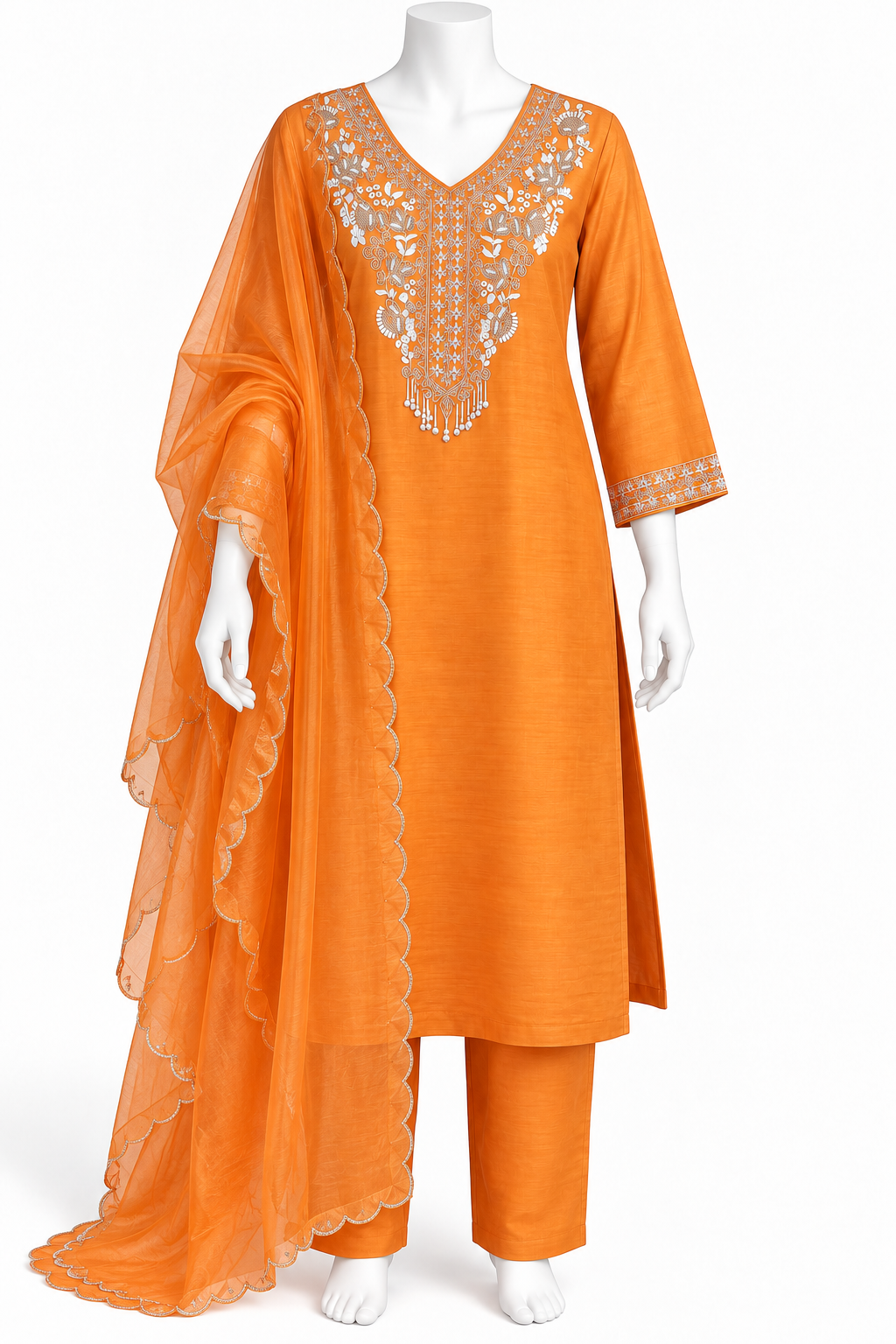 An orange three-piece women's salwar kameez suit set displayed on a white mannequin. The set includes an orange cotton kurta with silver embroidery on the chest and sleeve cuffs, matching orange trousers, and a sheer orange dupatta with a scalloped edge.
