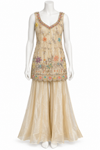 A sleeveless beige traditional outfit displayed on a white mannequin, featuring a heavily embroidered V-neck top with colorful floral motifs and a matching sheer flared skirt.