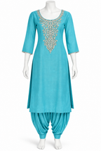 A turquoise blue kurta set displayed on a white mannequin, featuring a heavily embroidered neckline with gold and white details, paired with matching pleated patola pants.