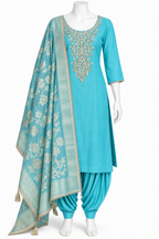 A turquoise blue Indian ethnic suit set displayed on a white mannequin, featuring a kurta with ornate gold embroidery, matching patola pants, and a coordinating dupatta with floral patterns and tassels.