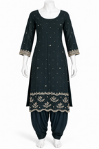A dark teal-green Indian ethnic kurta set displayed on a white mannequin, featuring a long tunic with gold embroidery, dot patterns, and a floral border, paired with matching flared pants.