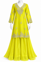 A bright yellow three-piece traditional outfit displayed on a white mannequin, featuring a long-sleeved kurta with silver embroidery, matching flared pants, and a coordinating scarf.