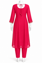 A bright pink three-piece kurta set displayed on a white mannequin against a plain white background. The set includes a long-sleeved tunic with a round neckline, tie-back detail, and gold embroidered cuffs, paired with matching straight-fit pants.