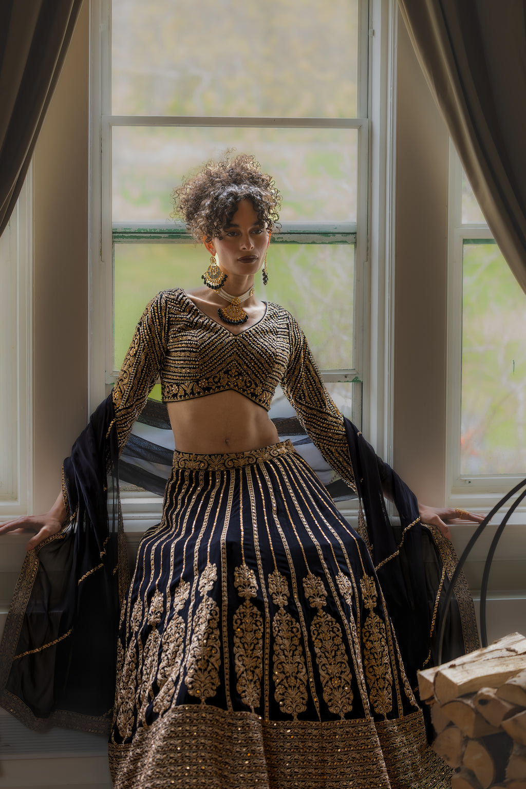 Woman in traditional outfit standing in a room with large windows.