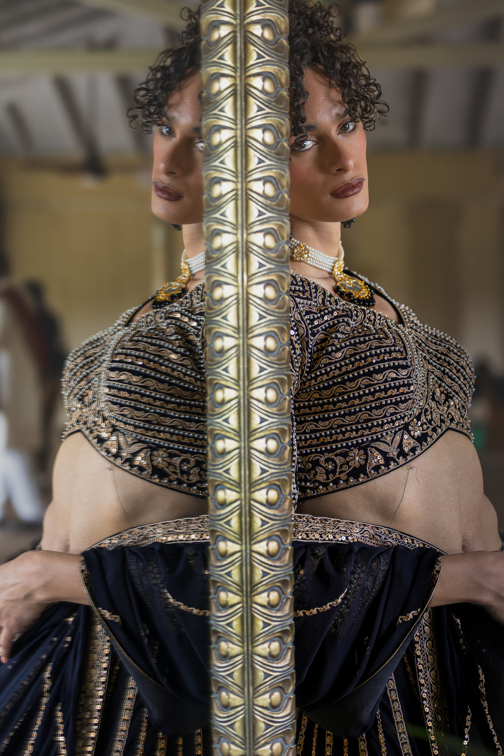 Woman wearing an ornate black and gold top with a long, detailed sword held across her chest.