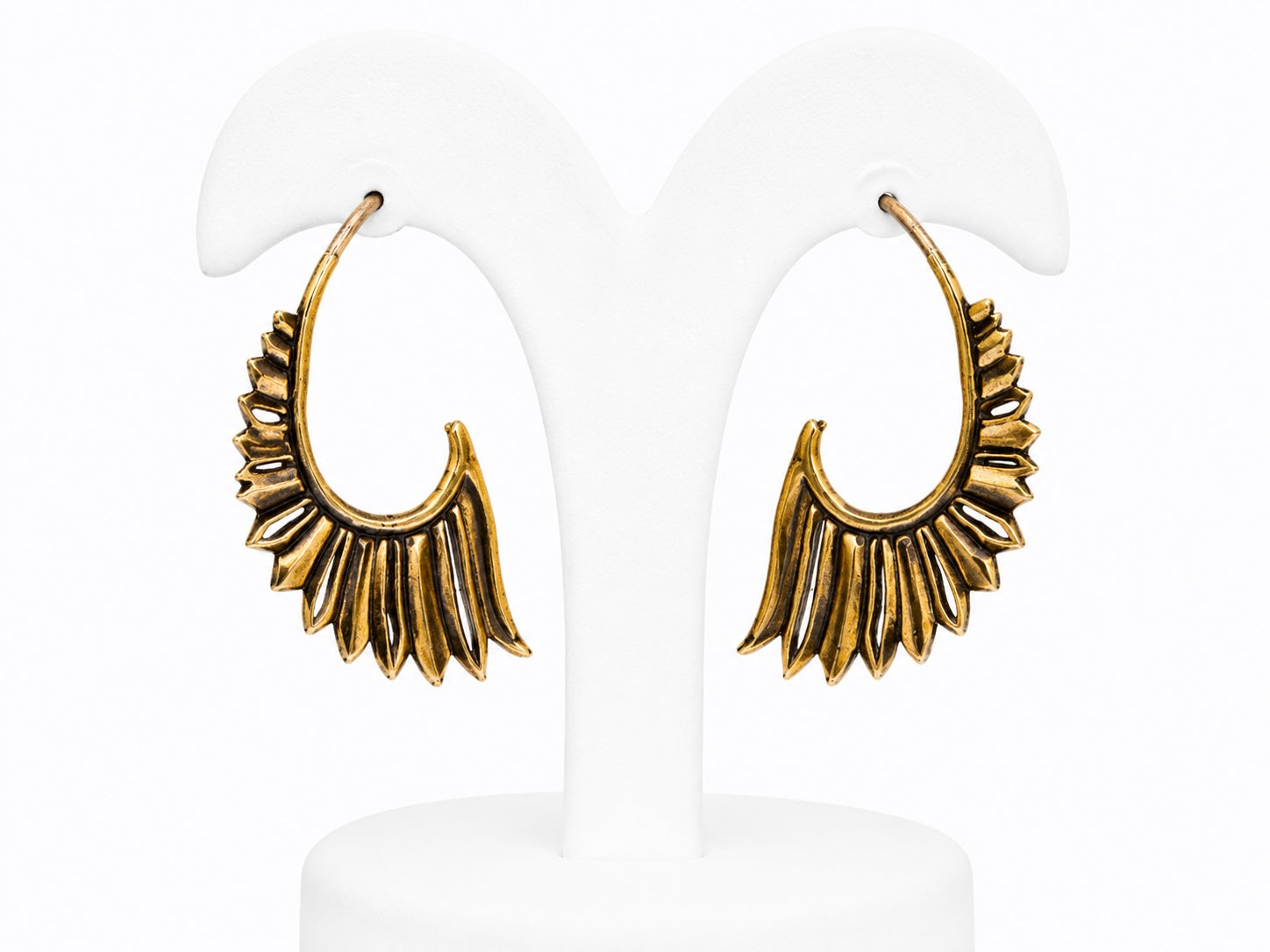 Gold hoop earrings on a white stand with a white background