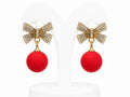 Pair of earrings with gold bows and red balls on a white background