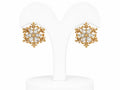 Gold snowflake earrings on a white stand with a white background