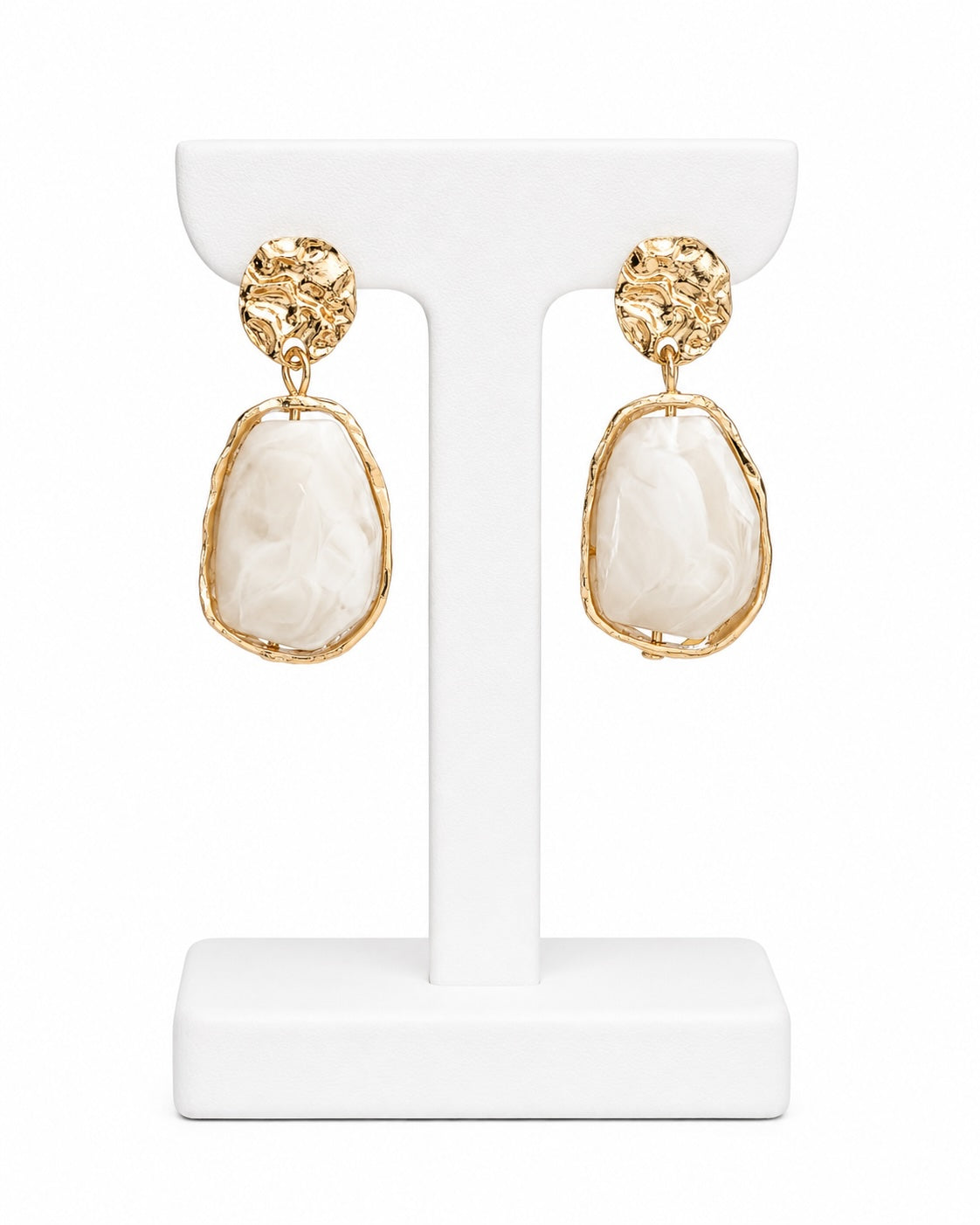 A pair of gold drop earrings with large, irregular cream-colored shell-like pendants, displayed on a white T-shaped jewelry stand against a white background.