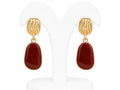 Gold earrings with red stones on a white background
