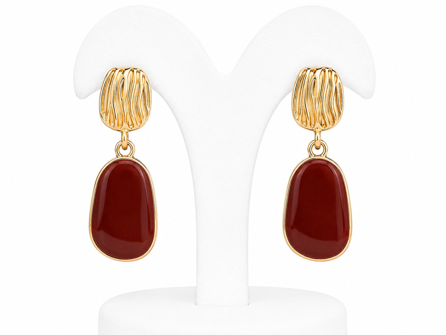 Gold earrings with red stones on a white background