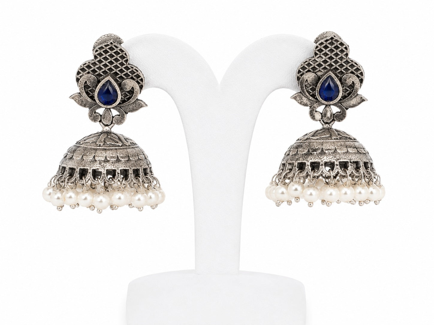 Pair of silver jhumka earrings with blue stones on a white background