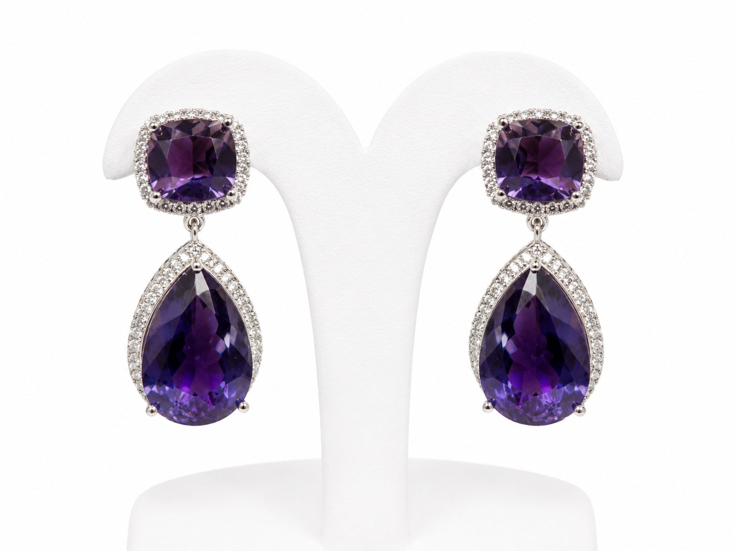 Pair of purple teardrop earrings on a white stand