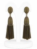 Pair of gold tassel earrings on a white stand