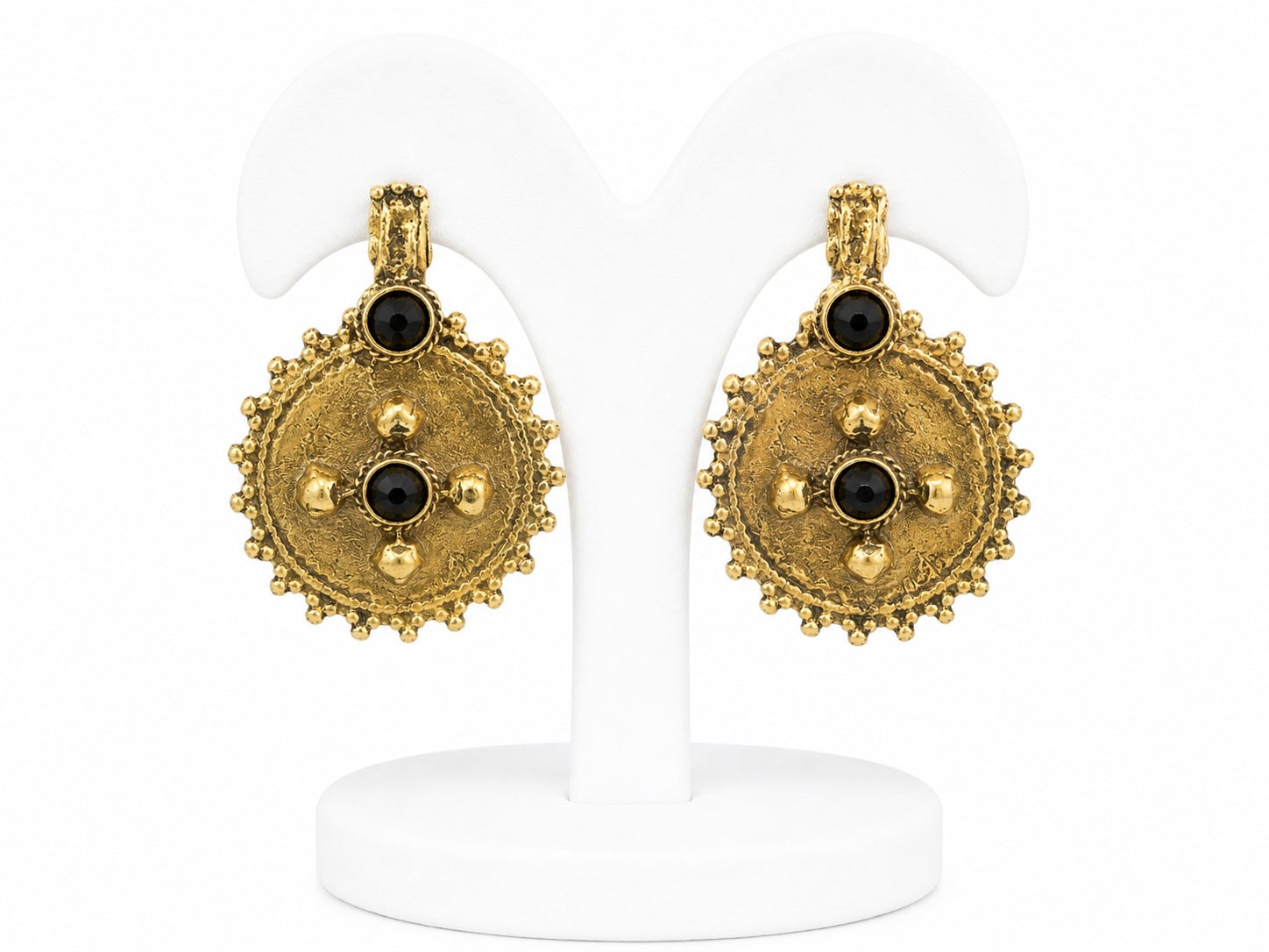 Pair of gold earrings with black gemstones on a white stand