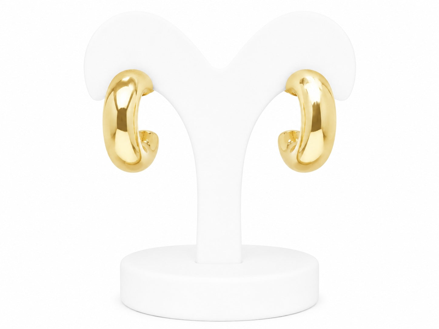Gold hoop earrings on a white stand with a white background
