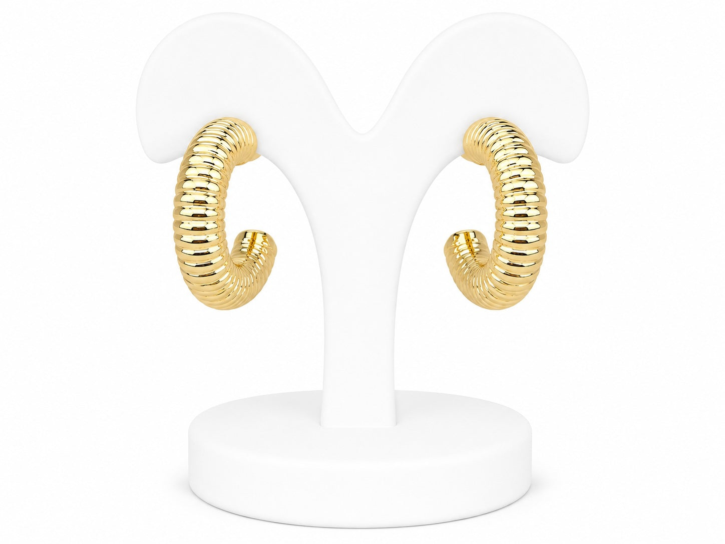 Gold hoop earrings on a white stand against a white background